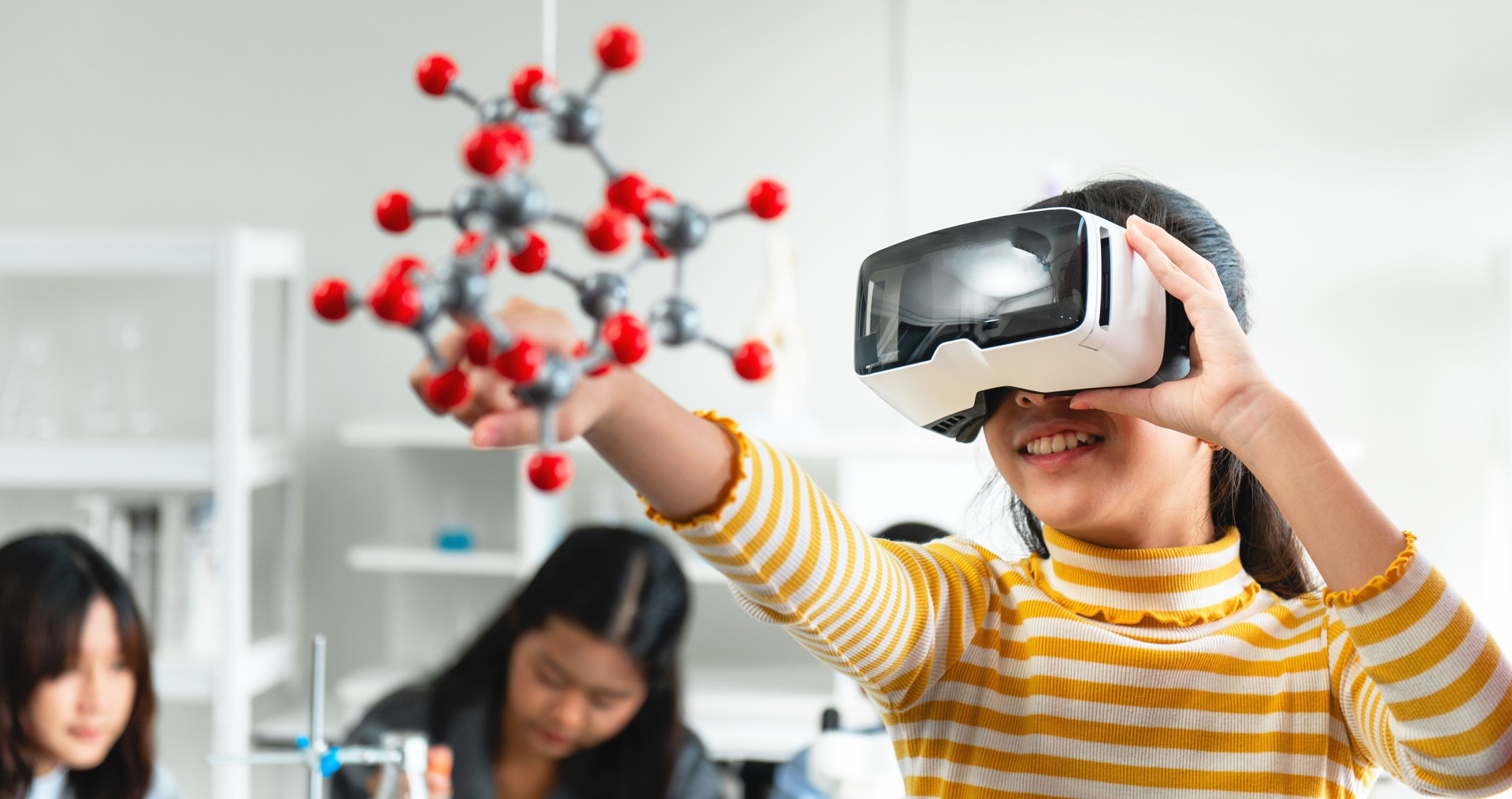 girl is wearing a yellow shirt and holding a virtual reality headset